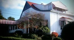 A white house with red roof and blue shutters.