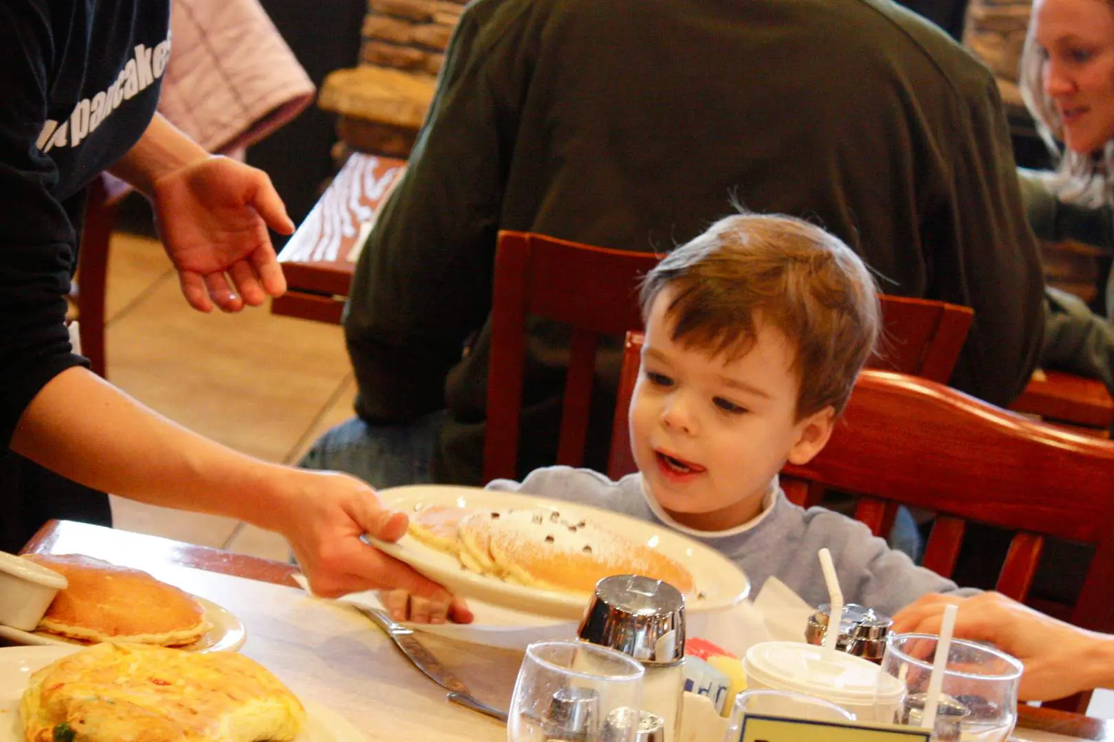 A child at the table eating food from a plate.