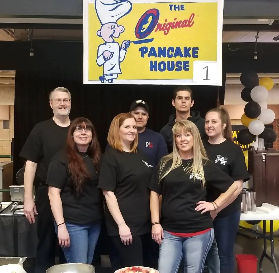 A group of people standing in front of a sign.